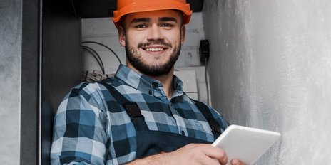 Ein Elektroniker der in einem Serviceraum ein Tablet bedient